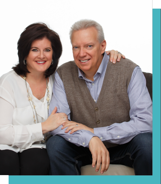 A smiling couple posing together on a white background.