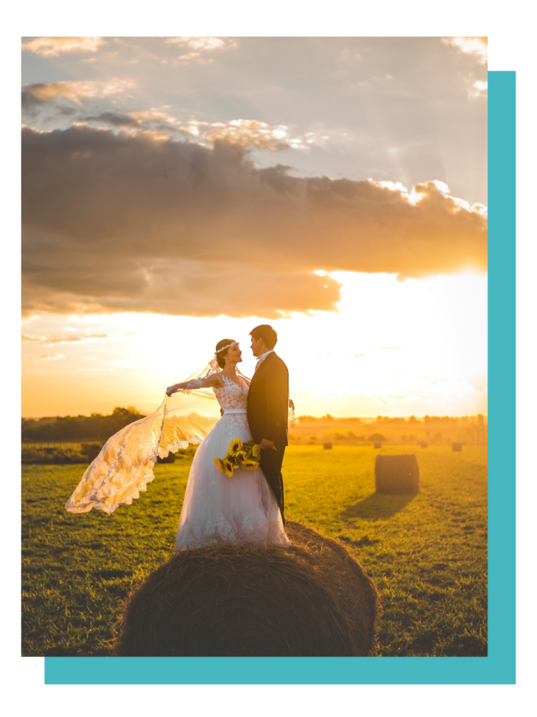 A couple in wedding attire stands romantically in a sunlit field, evoking themes of love and union.