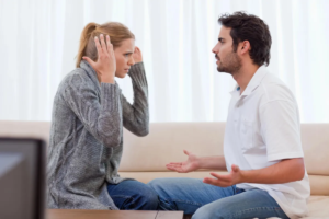 A couple is having a heated discussion or argument while sitting on a couch.