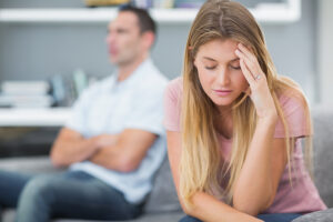 Married couple sitting on the sofa, not speaking to each other.