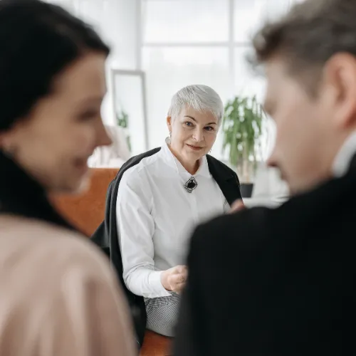 Three people are engaged in a serious conversation, possibly in a counseling setting.