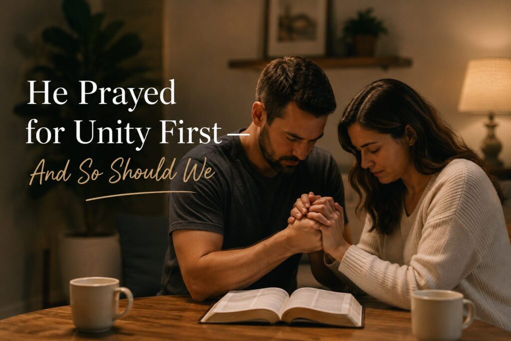 A couple sitting at a table holding hands and praying together.